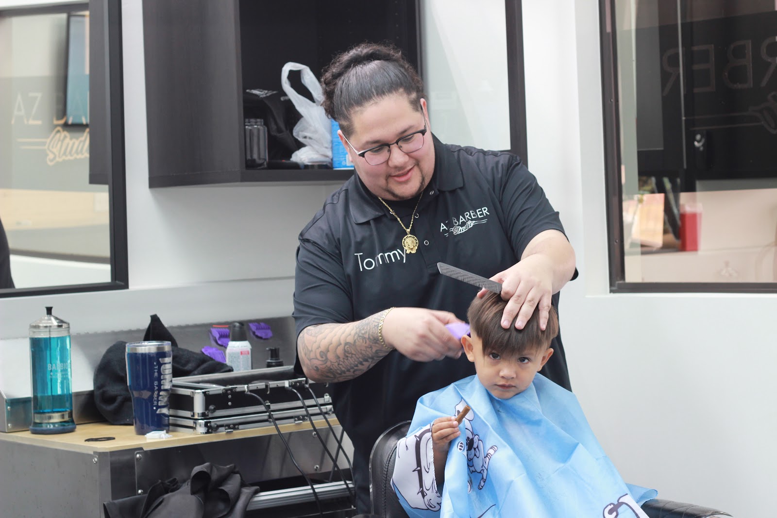 Tommy combing out a toddler's cut while the little guy holds his snack