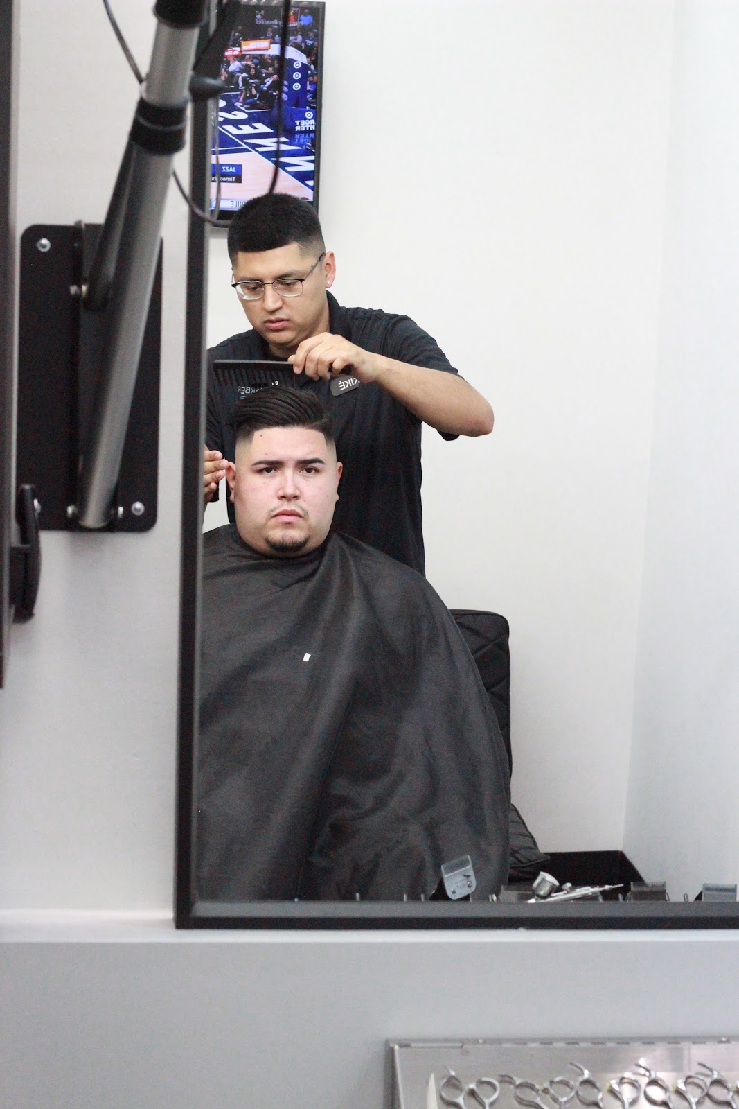 Slicked-back pompadour with a high fade, checked in the station mirror