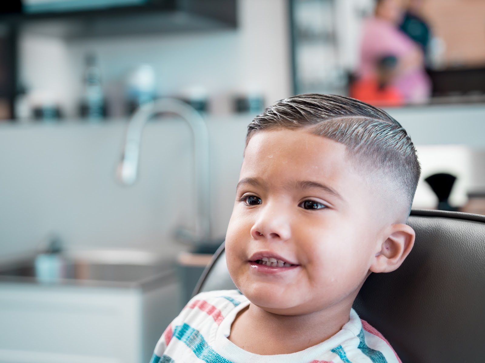 A little one smiling with his fresh comb-over fade
