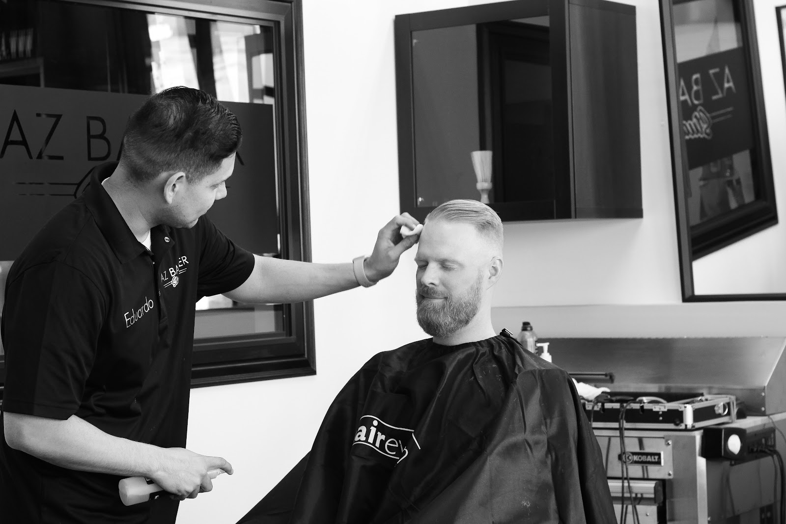 Eduardo finishing a client's slick back, shot in black and white