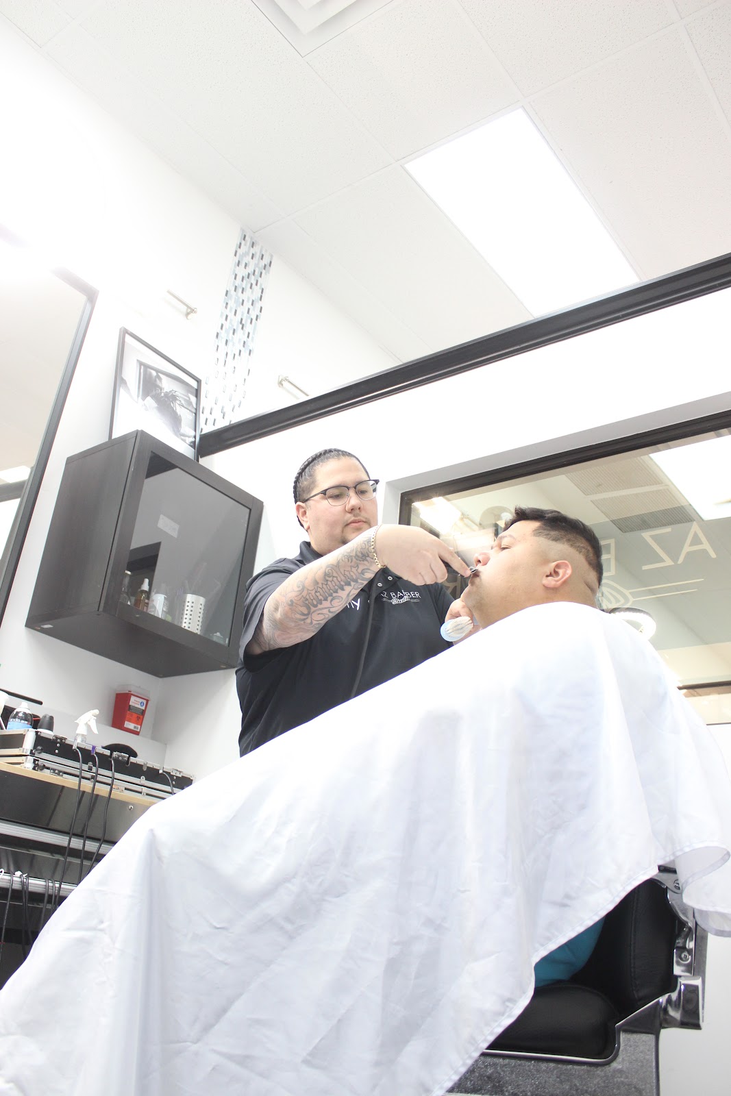 A straight razor detail during a shave, client reclined under a fresh cape